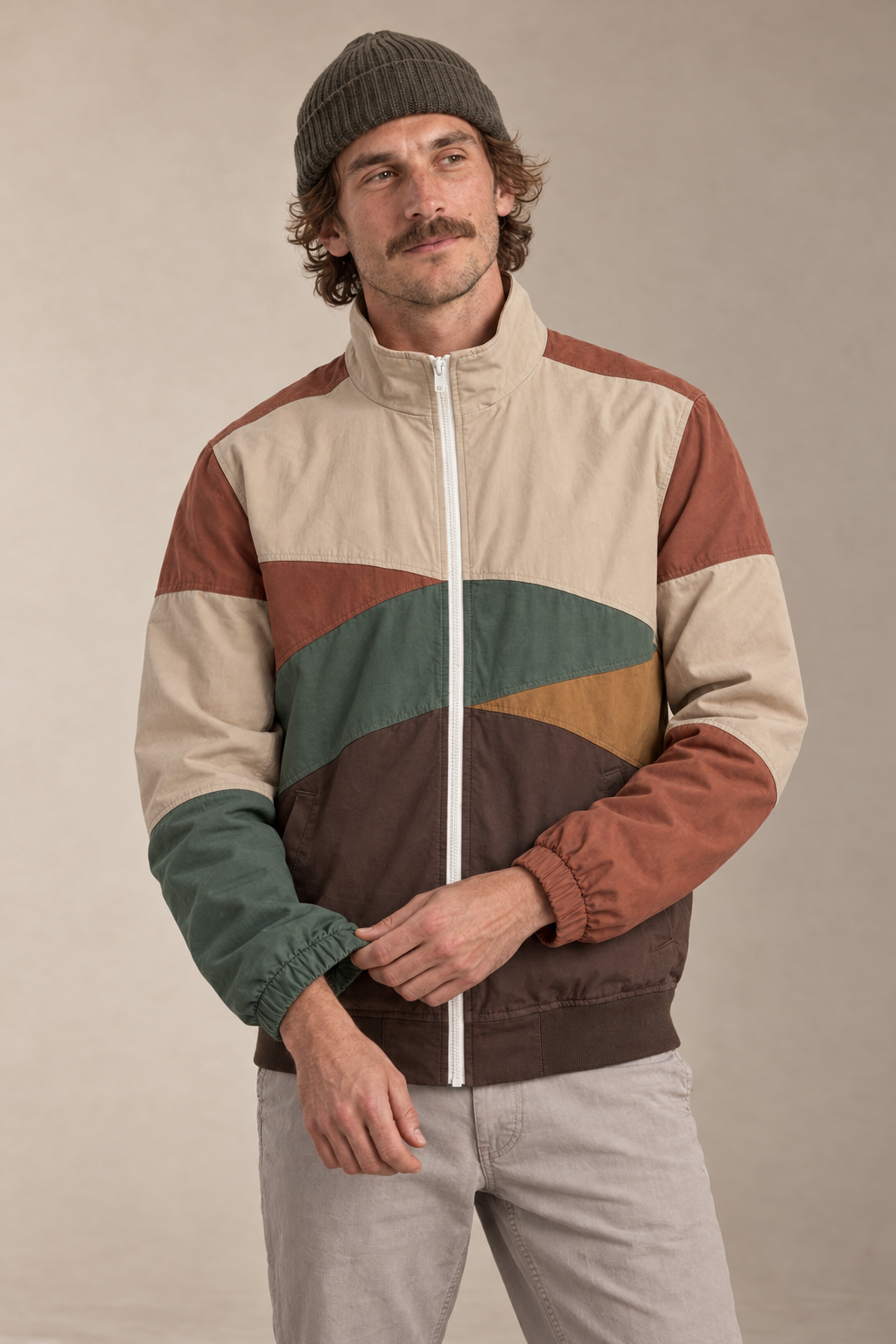 Model adjusting the cuff of the earth-tone Wayfarer jacket in a warm studio.